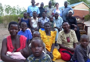 På gruppbilden ser vi ,från vänster längst bak,  Boniface Gum, Lino Kehmis, Isaac Olobo, Matilda Utbult från Sverige, och. Ponsiano Okalo. I mitten  sitter Janet Akello, Brenda Ajangi, Palma Atoke, pojken Sheriffa, Angelos Kula och Amina Delino. Längs fram sitter Hariet Gum, Dunlas Atepo, Jacinta Awor och Nightie Ocengum –  tilllsammans med några barn. I bakgrunden ett nybyggt gemensamt byhus.